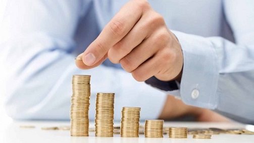 A few small stacks of coins that increasingly get larger, with a person adding a coin to the tallest one