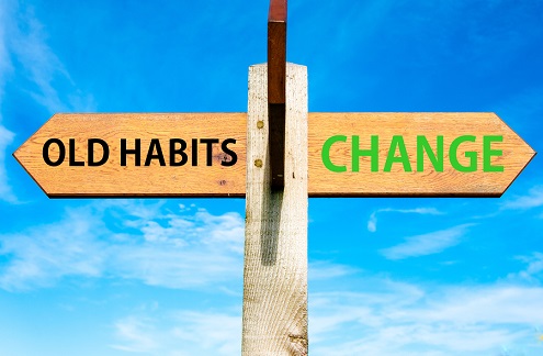 A sign with an arrow pointing to the left that says "old habits" and an arrow pointing to the right that says "change"