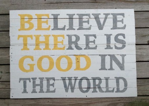 A sign that says "believe there is good in the world" in gray letters with "be the good" in yellow letters
