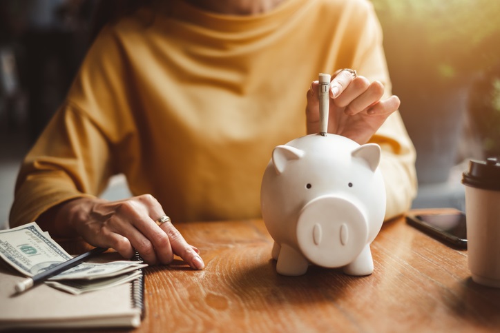 Photo of a women putting money into a piggy bank