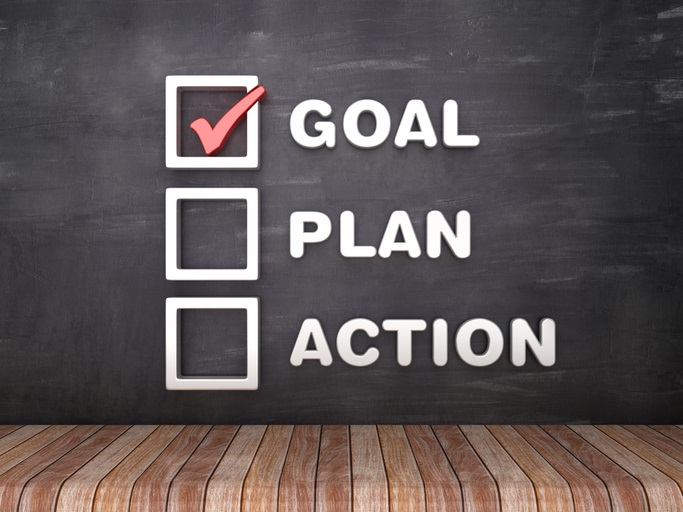 The words "goal", "plan", and "action" written on a chalkboard with checkboxes next to each