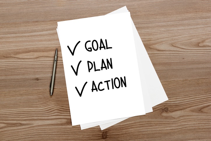 Photo of a pen and paper with "goal, plan, action" written on it