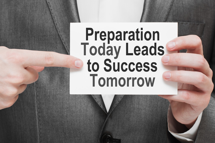 A person holding a sign that says "preparation today leads to success tomorrow"