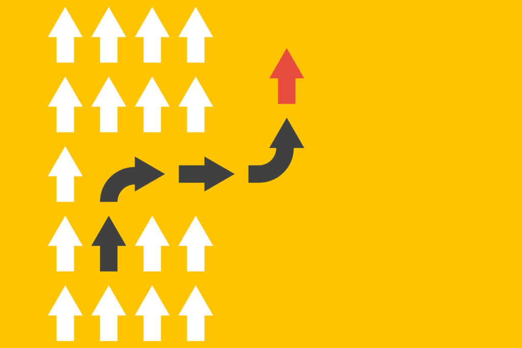 A yellow background with a group of white arrows going in the same direction. A few black arrows turn from the group in a different direction