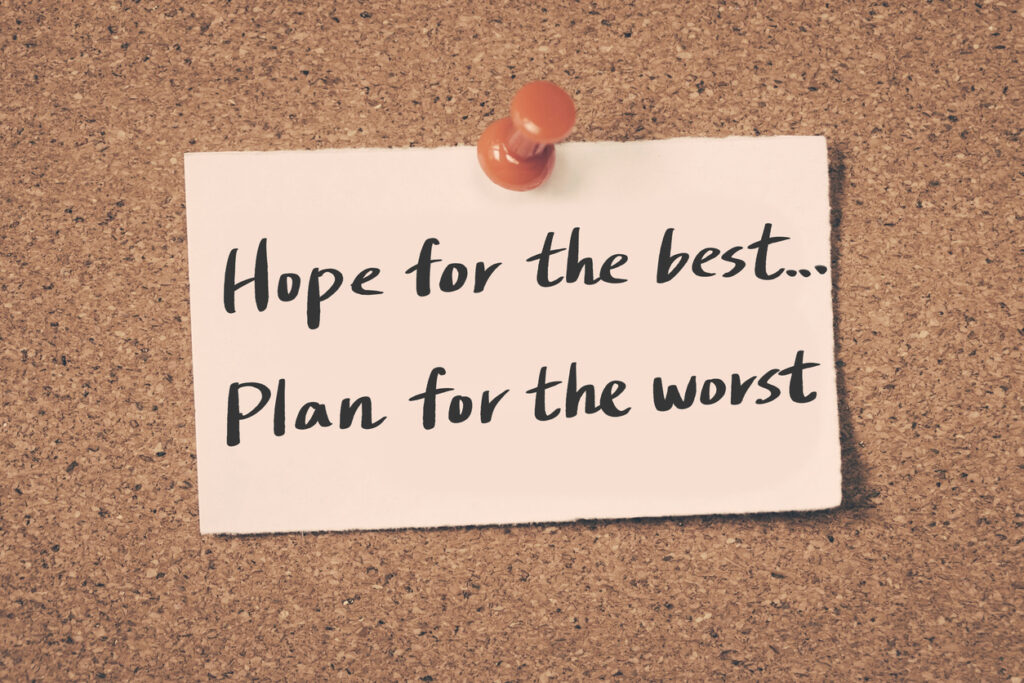 A note that says "Hope for the best... Plan for the worst" pinned to a corkboard with a red push pin