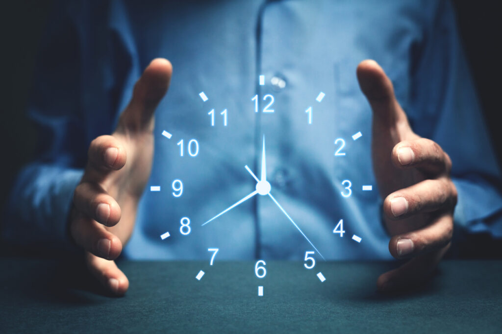 A person holds their hands around a glowing, holographic clock, suggesting themes of time control, urgency, or time management.
