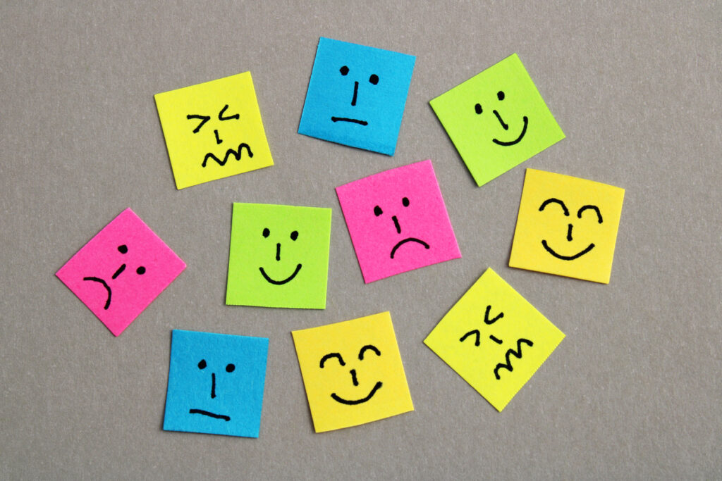 Group of colorful papers with different facial expressions against a gray background