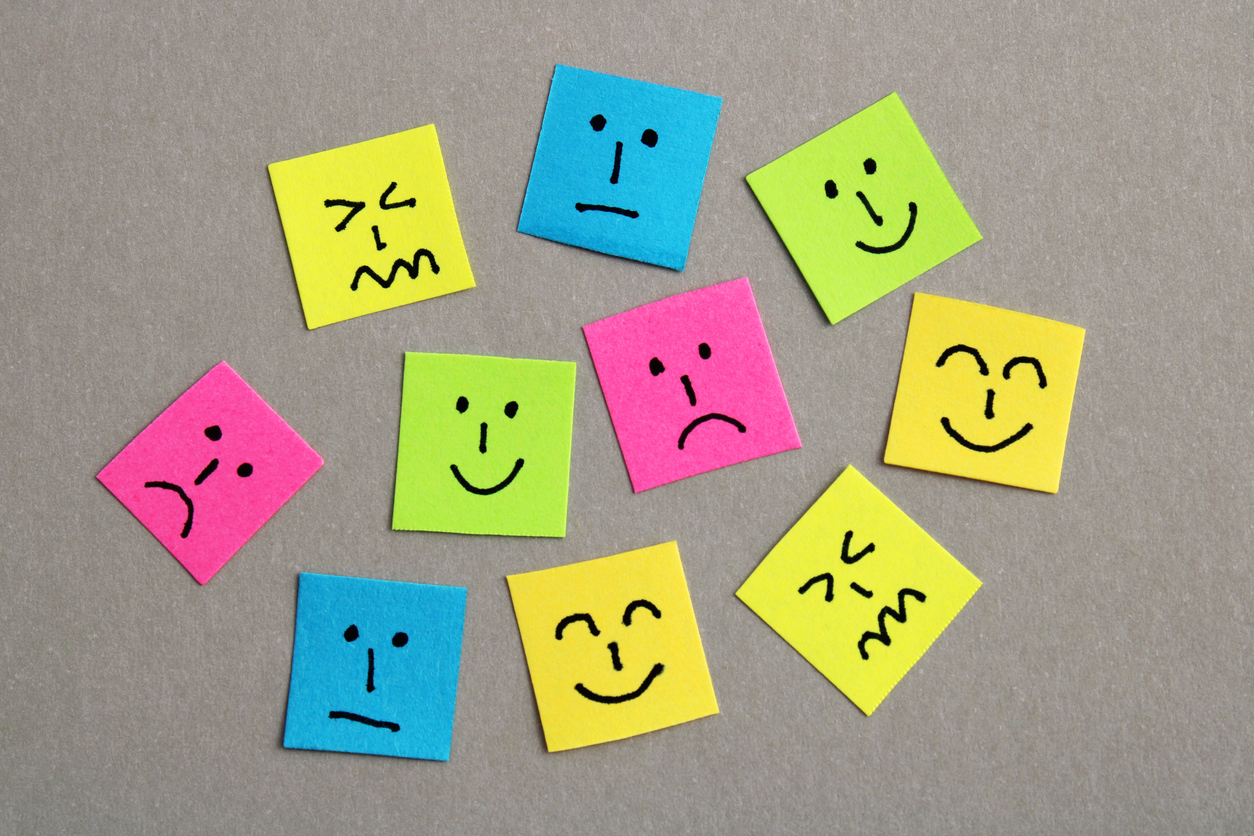 Group of colorful papers with different facial expressions against a gray background