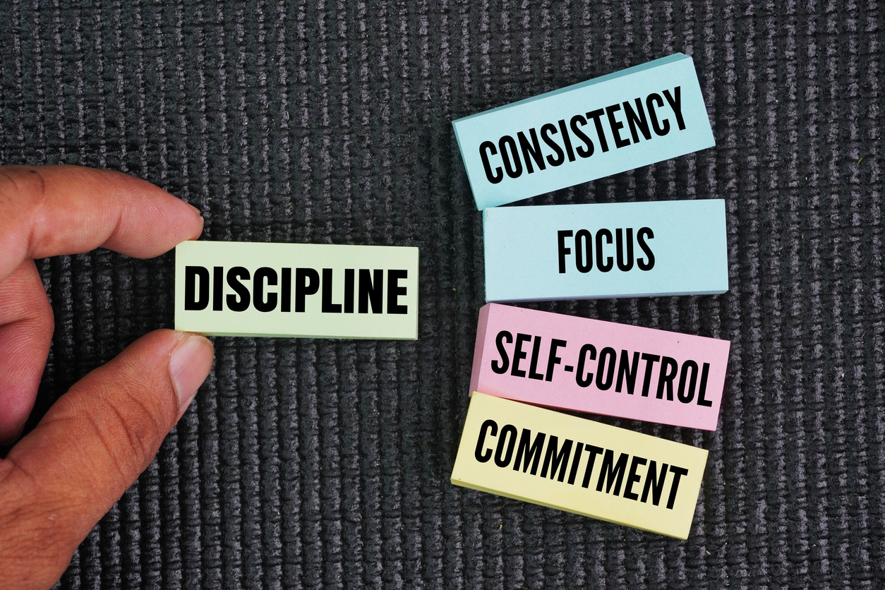 A hand holds a card labeled “Discipline,” beside cards reading “Consistency,” “Focus,” “Self-Control,” and “Commitment.”